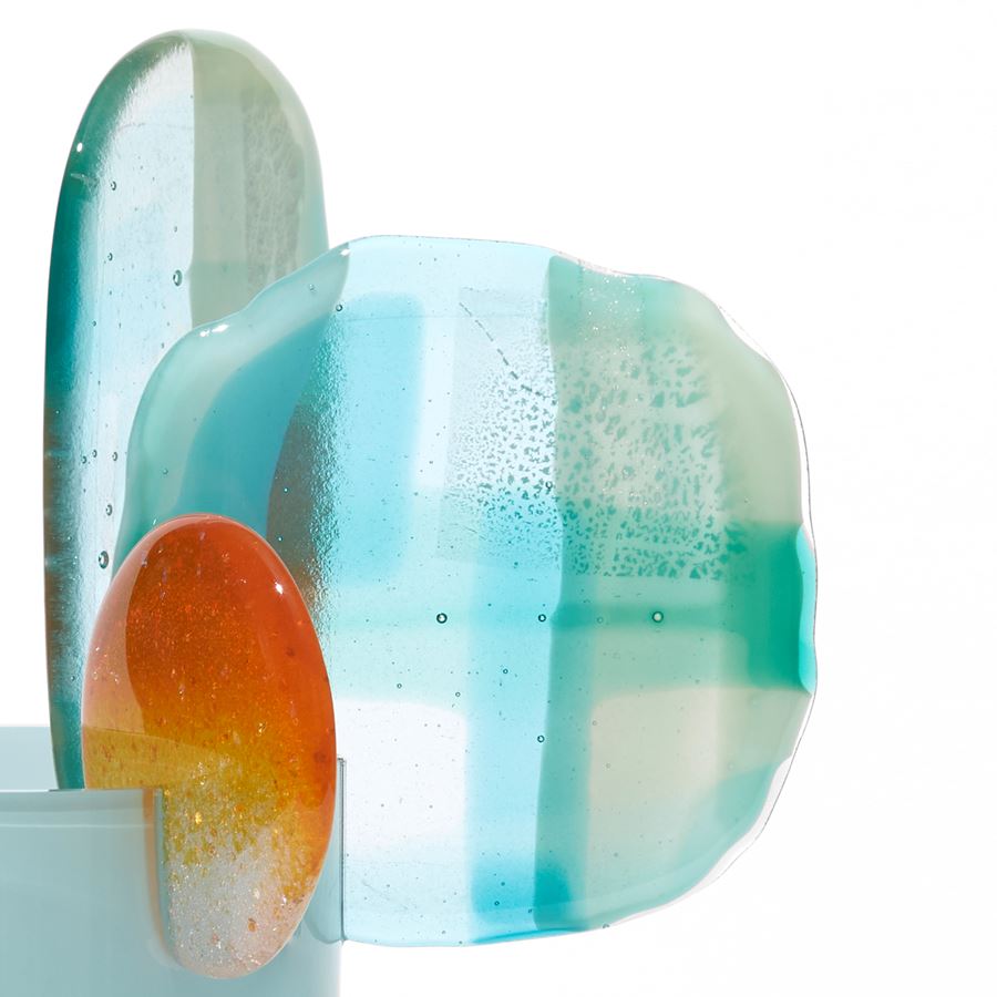 short opaque celadon cylinder with three rounded abstract finials in a mix of orange aquamarine jade turquoise white and clear hand made from blown and fused glass